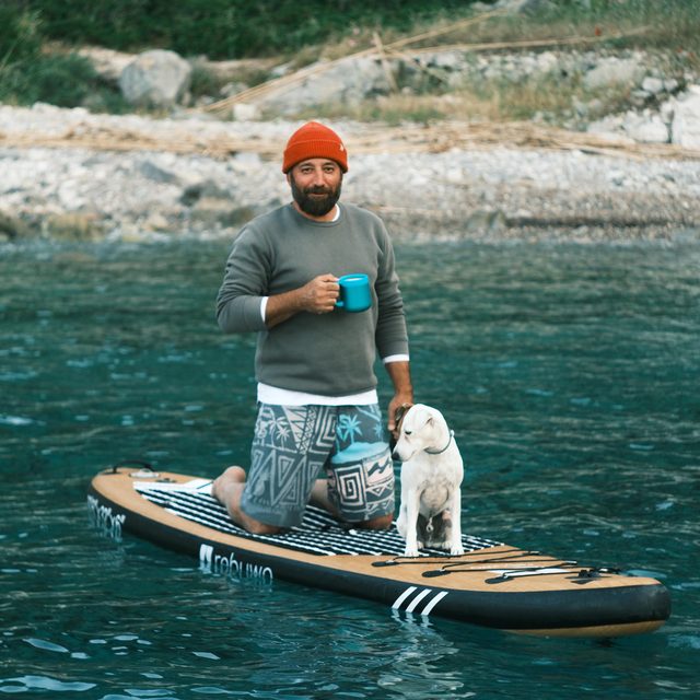 Ismail on a paddleboard at anchor, a dog on the nose