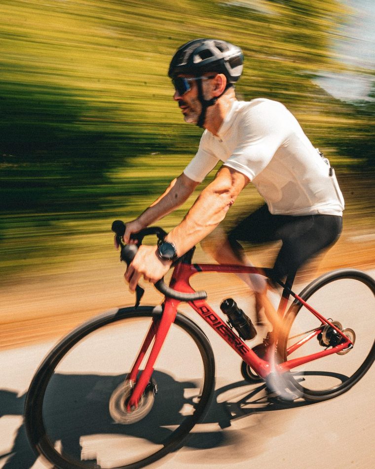 A road cyclist at speed, the roadside trees blurred behind