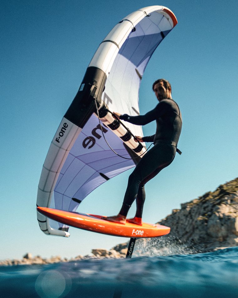 A wing foiler lifted clear of the water on the foil